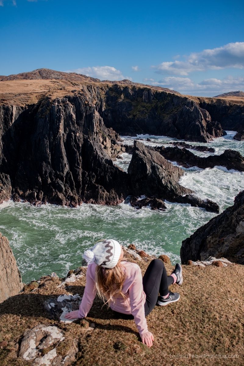 Woman on cliff overlooking rugged Irish coast