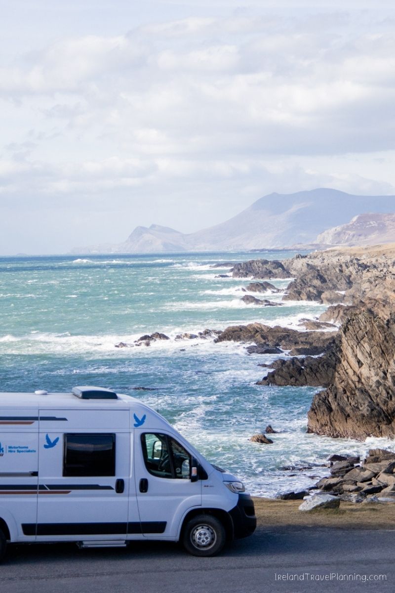 Campervan parked by the rugged Irish coast, a scenic drive option.