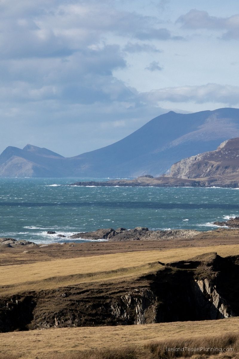 Rugged Irish coastline with rolling hills and mountains under a cloudy sky