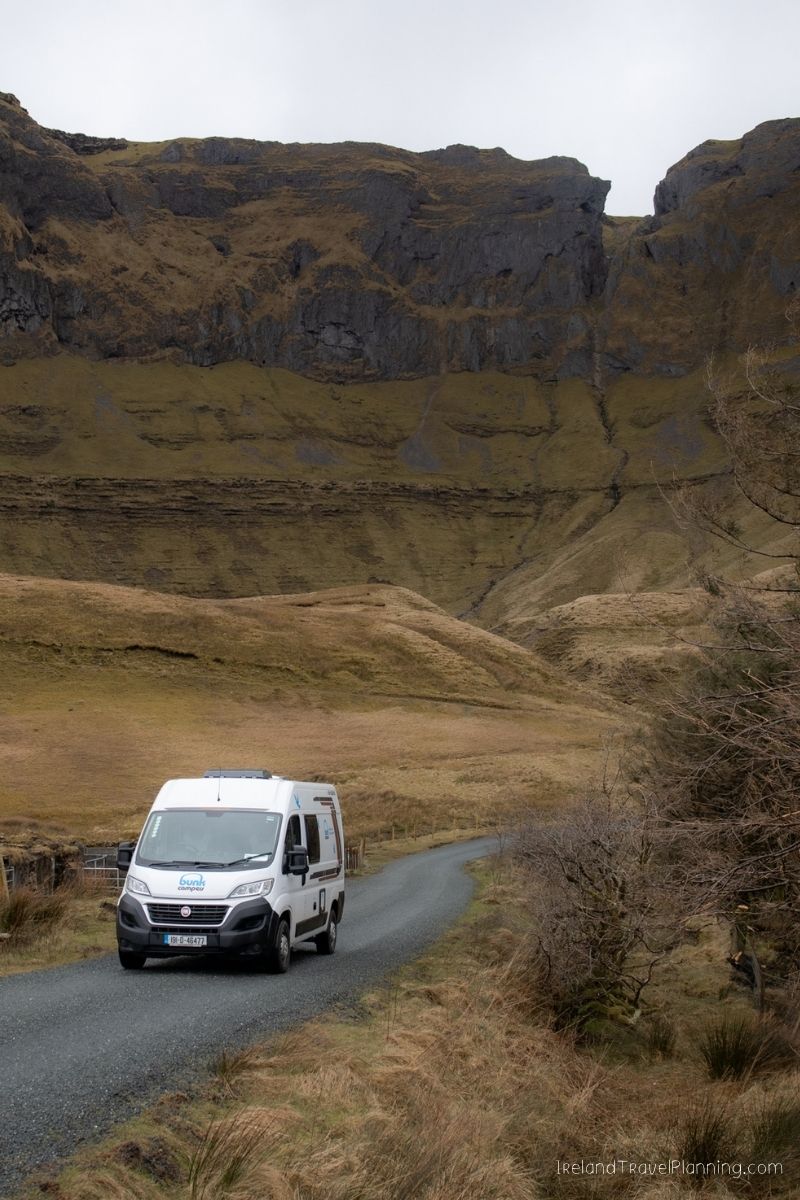 Campervan driving on a rural road in Ireland with dramatic cliffs