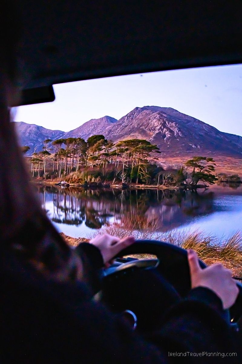 Driving through Connemara, Ireland with mountains and a lake.