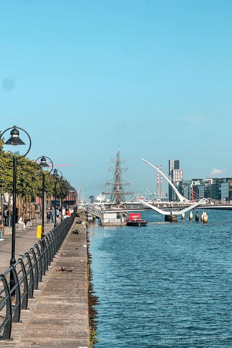 Samuel Beckett Bridge and a tall ship in Dublin's Docklands on a sunny day.