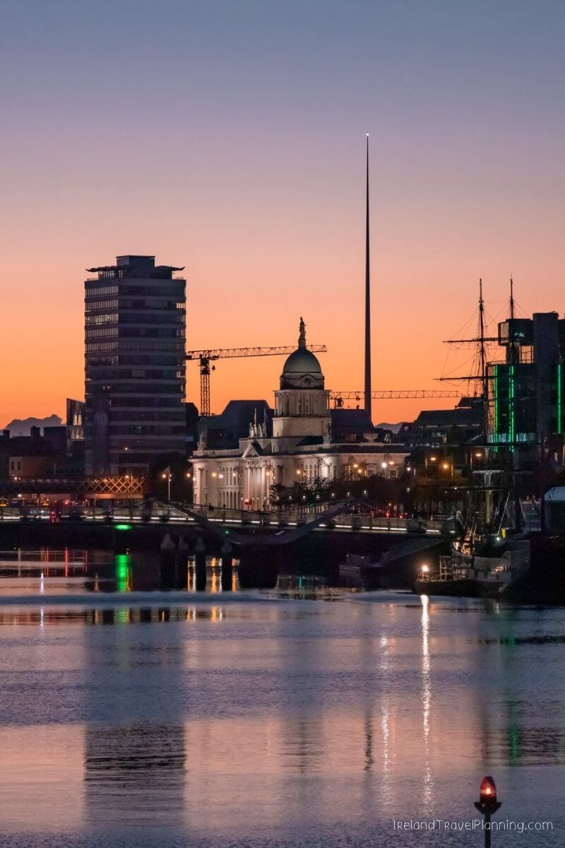 Dublin skyline at sunset with Spire, Custom House, and River Liffey.