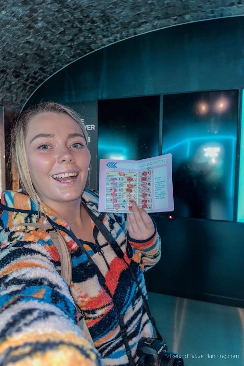 Woman smiling and holding a map inside a museum with blue lighting