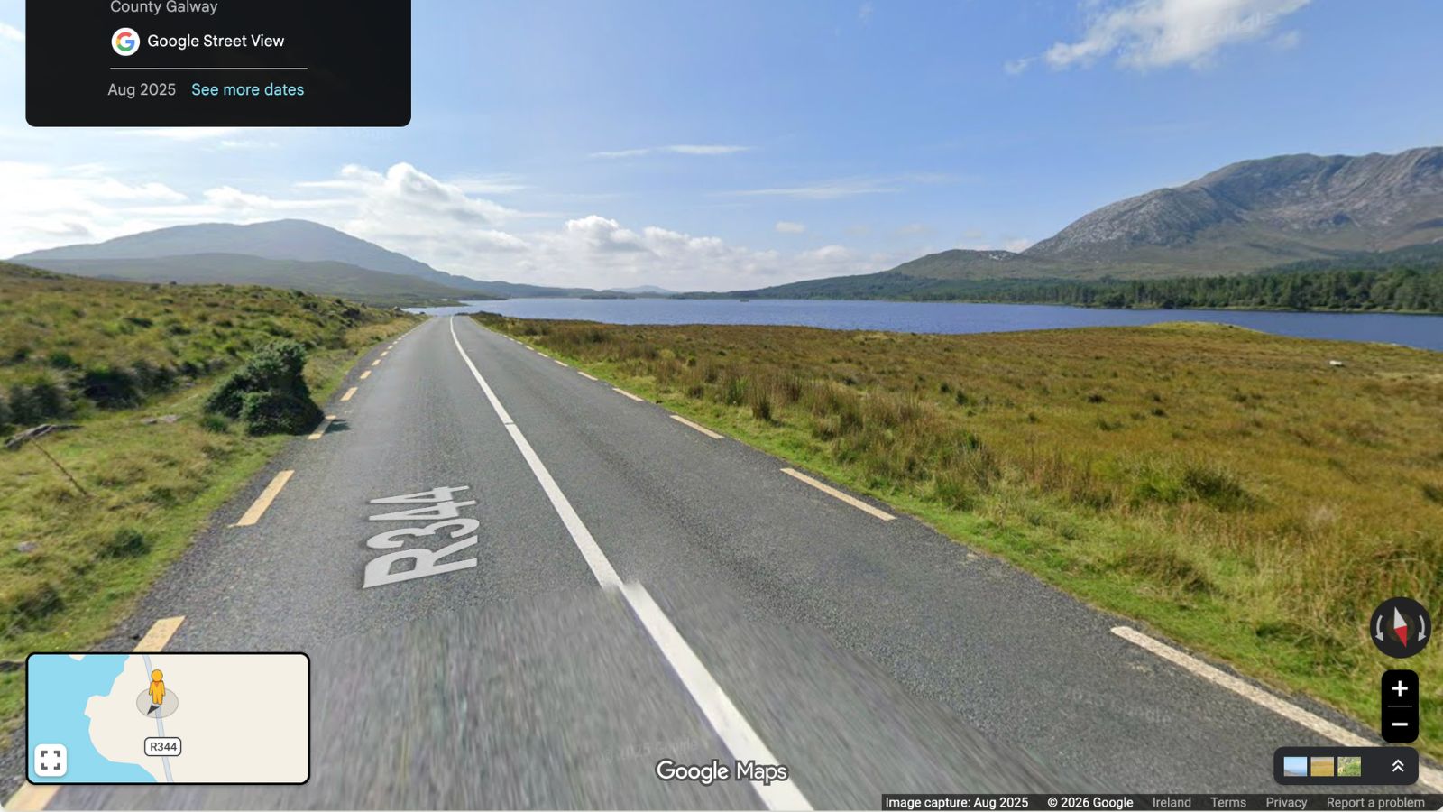 R344 road in County Galway, Ireland, leading to a scenic lake and mountains