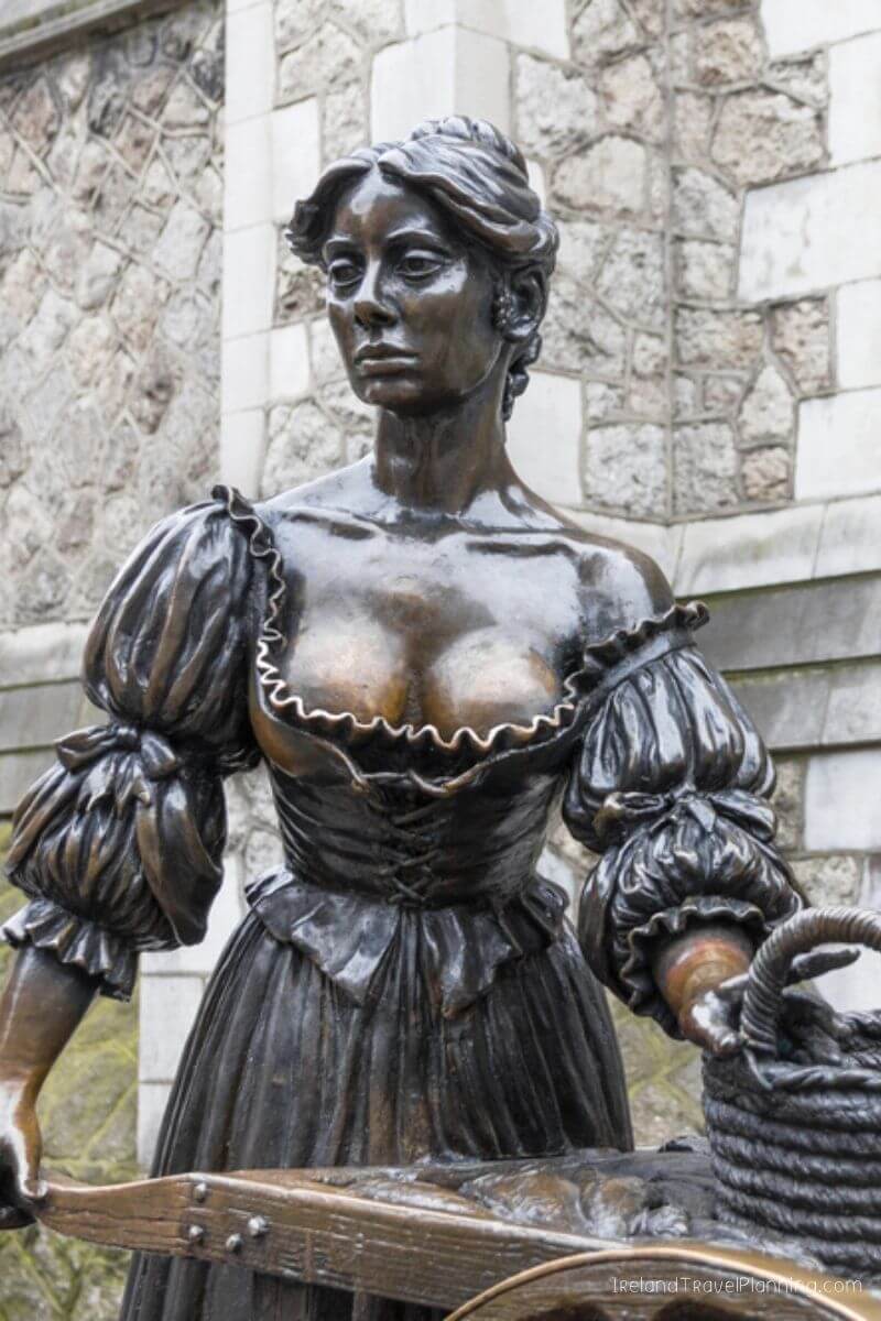 Bronze statue of a woman in historical dress carrying a basket