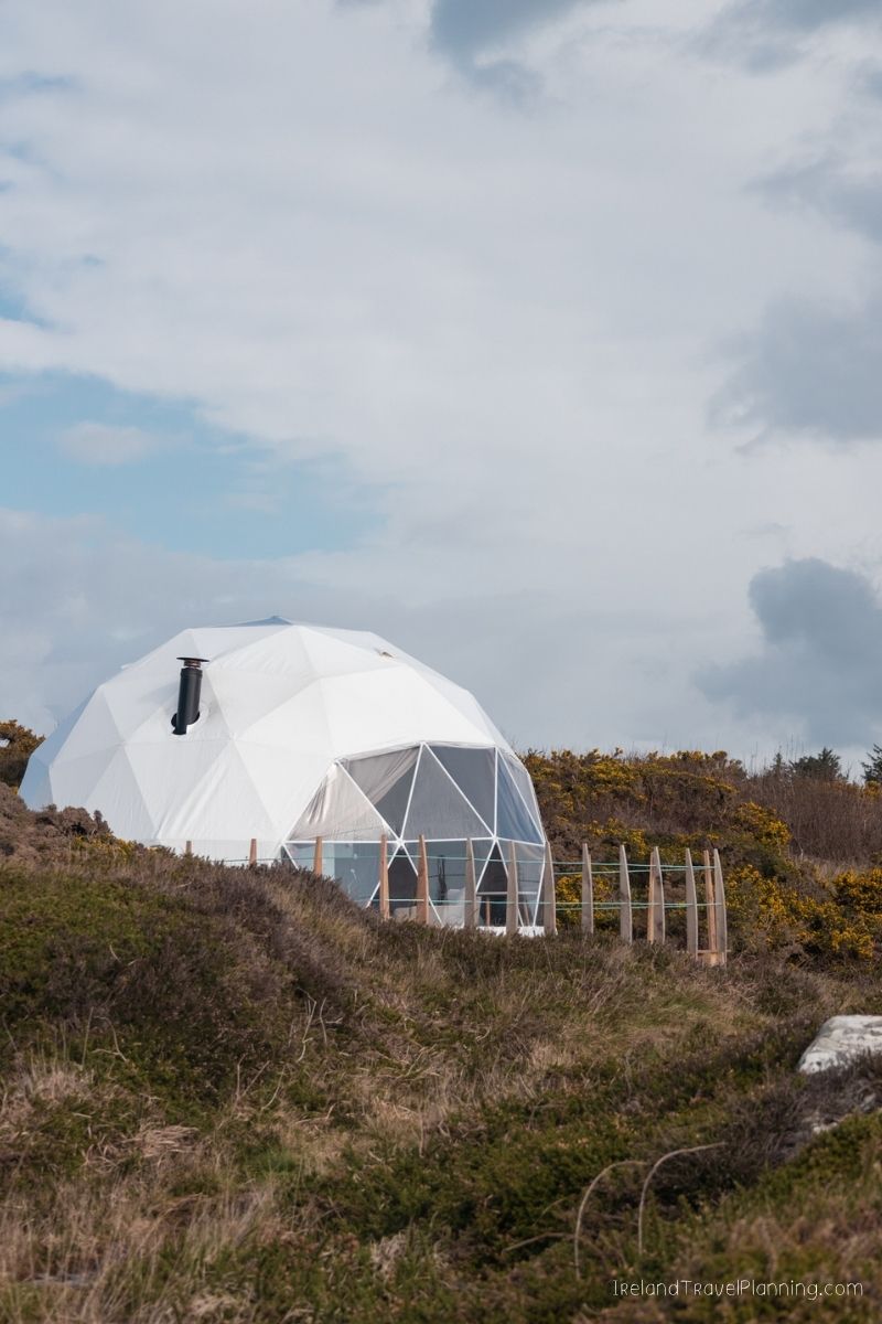 White geodesic dome glamping tent on a grassy hill in Ireland