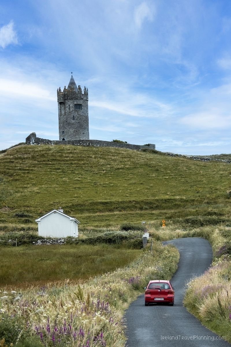 Doolin Tower and a red car on a winding road in rural Ireland.