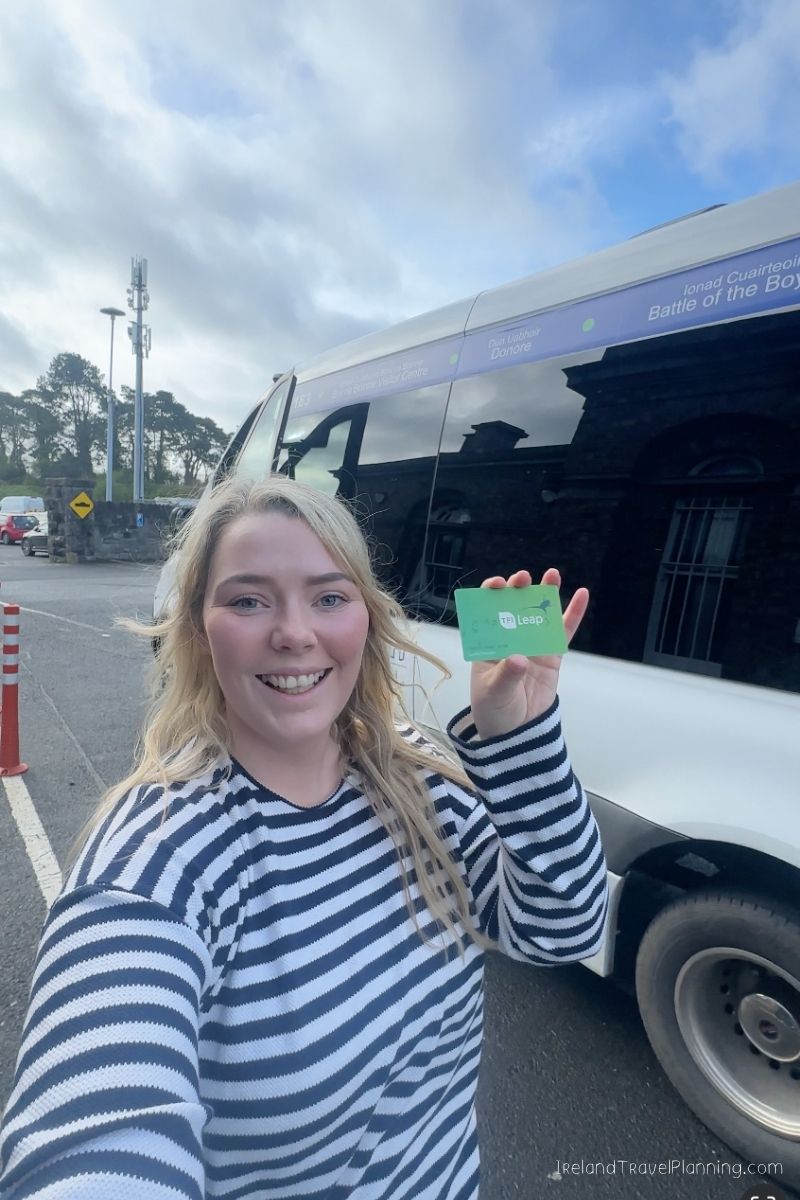 Woman holds a Leap Card in front of a bus in Ireland, part of an Ireland trip cost discussion.