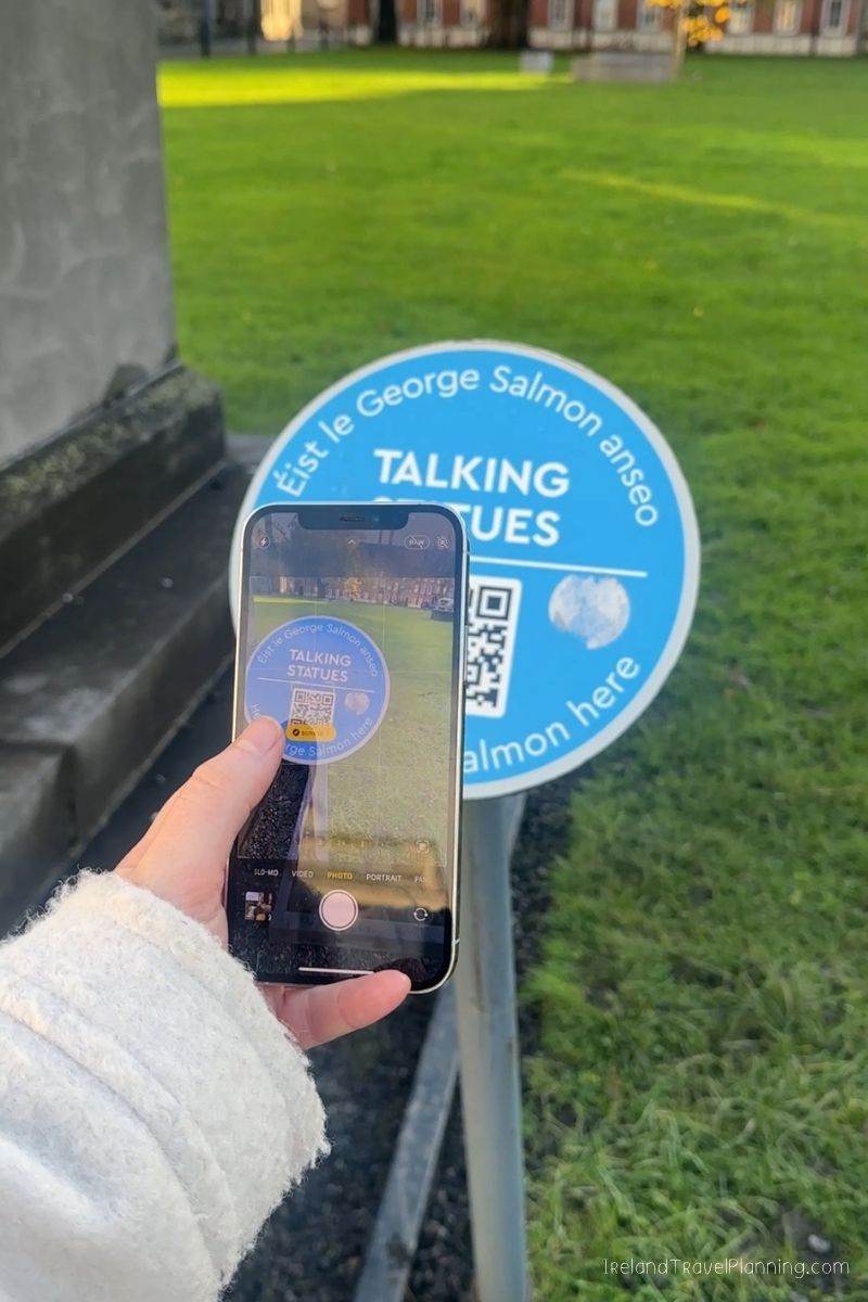 Phone scanning QR code on "Talking Statues" sign in Ireland