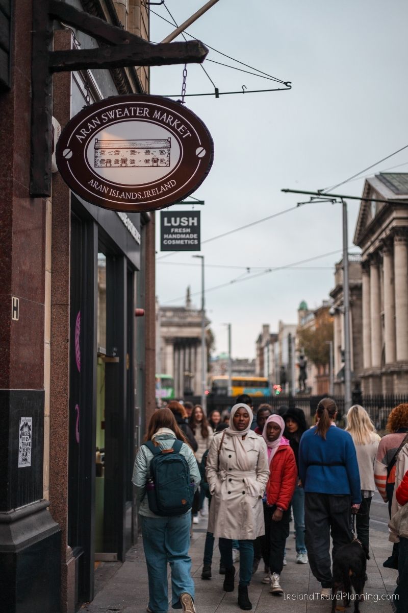 Aran Sweater Market sign in Ireland, people walking past