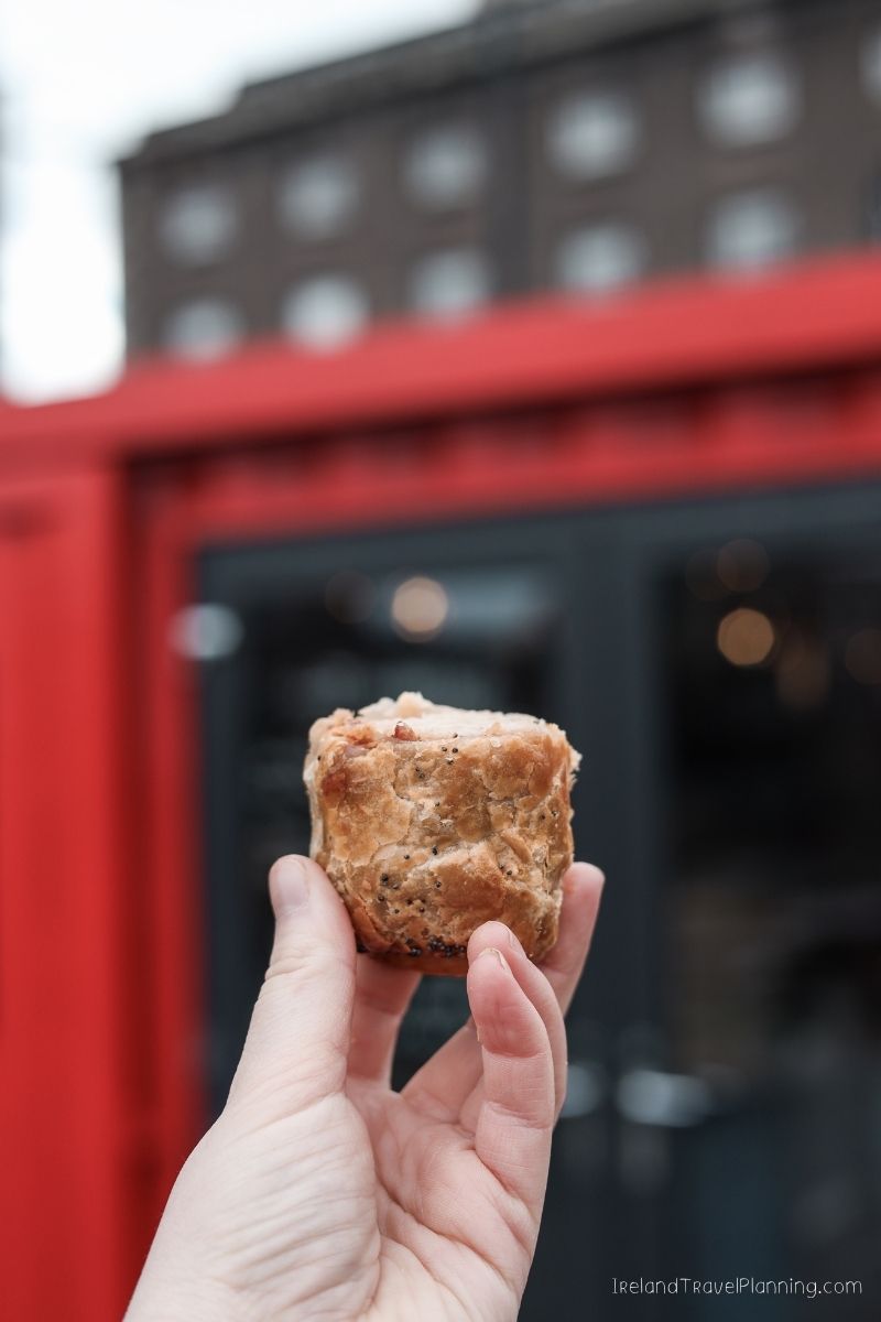 Hand holding a savory pastry with poppy seeds, possibly a snack from an Ireland trip.