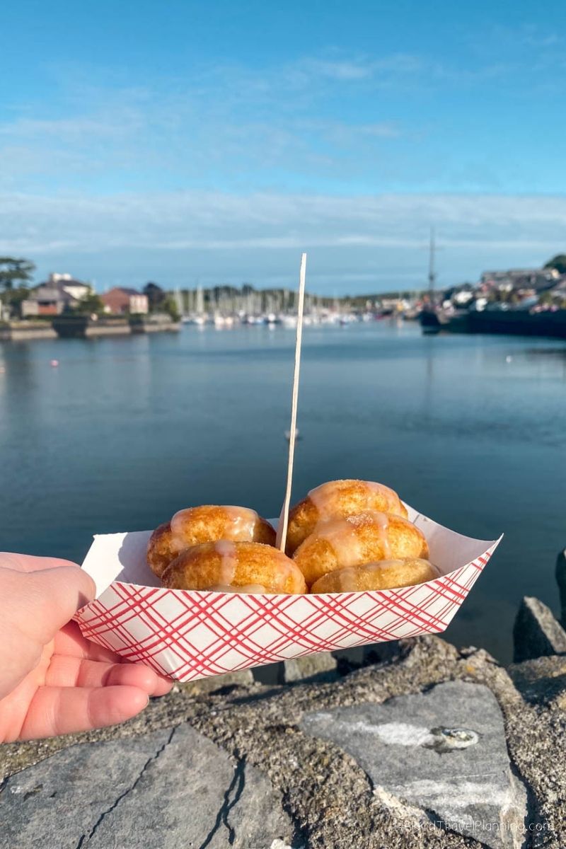 Doughnuts in a boat-shaped paper tray overlooking a harbor in Ireland