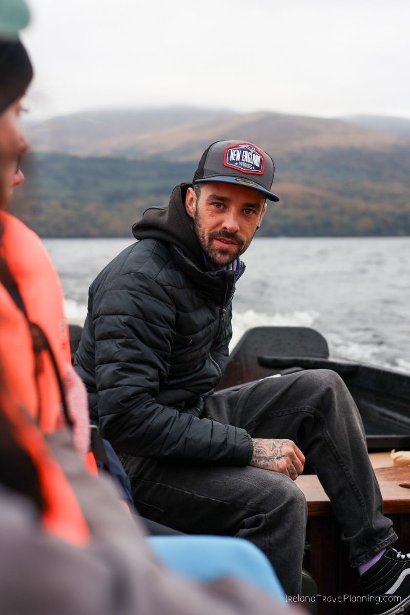 Man on a boat in Ireland with mountains in the background