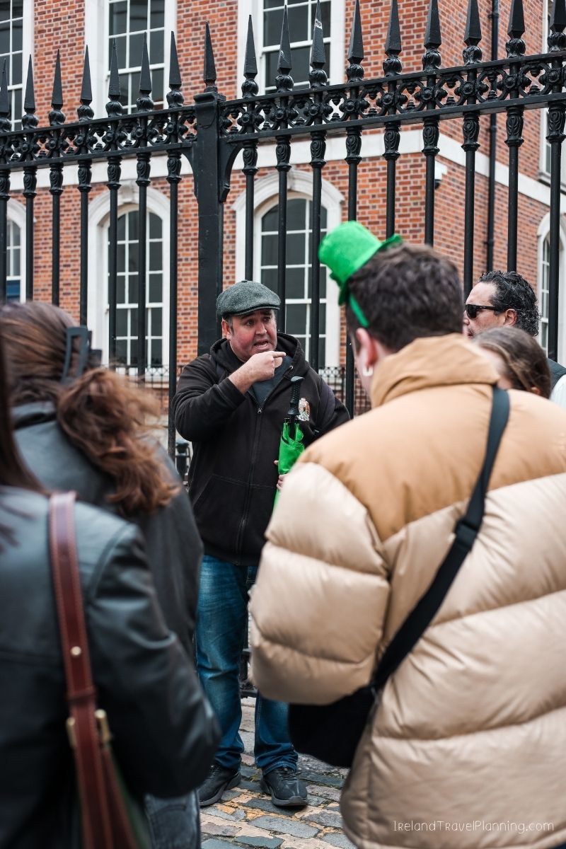 Tour guide in Dublin, Ireland, with a green hat and shamrock, discussing trip costs.
