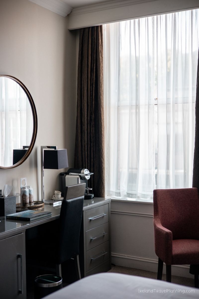Hotel room desk with mirror and chair, part of an Ireland trip cost discussion.