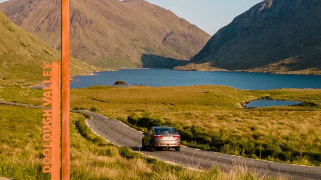 Car driving on a scenic road in Doolough Valley, Ireland.