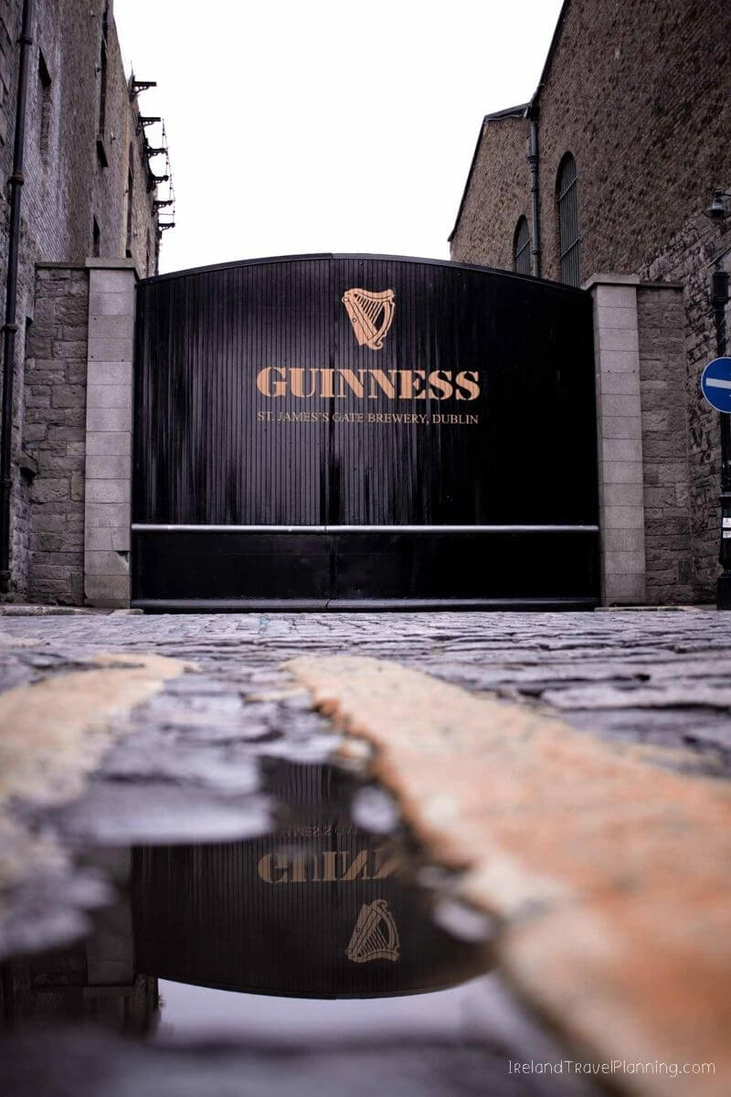 Guinness Storehouse Dublin entrance gate with harp logo and cobblestone street reflection