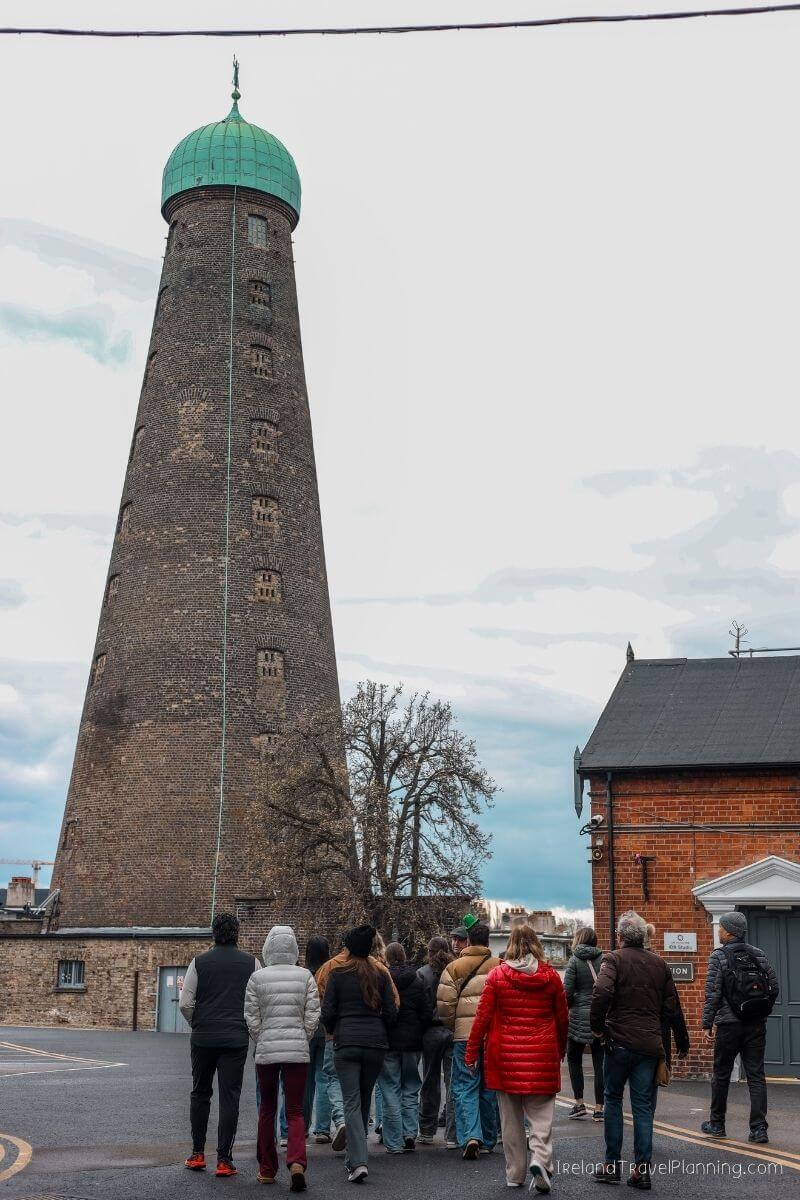 Tourists walk towards the historic Guinness Storehouse tower in Dublin, Ireland.