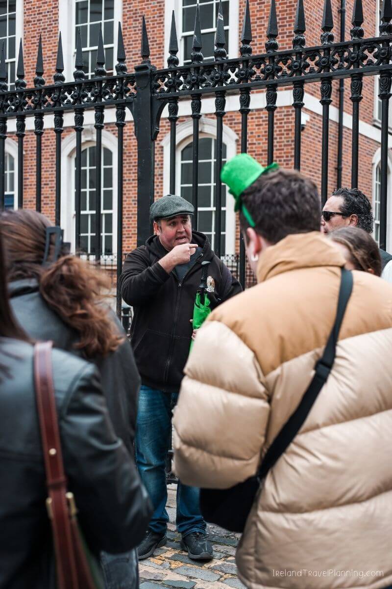 Tourists in Dublin, Ireland, near a historic building with a black fence.