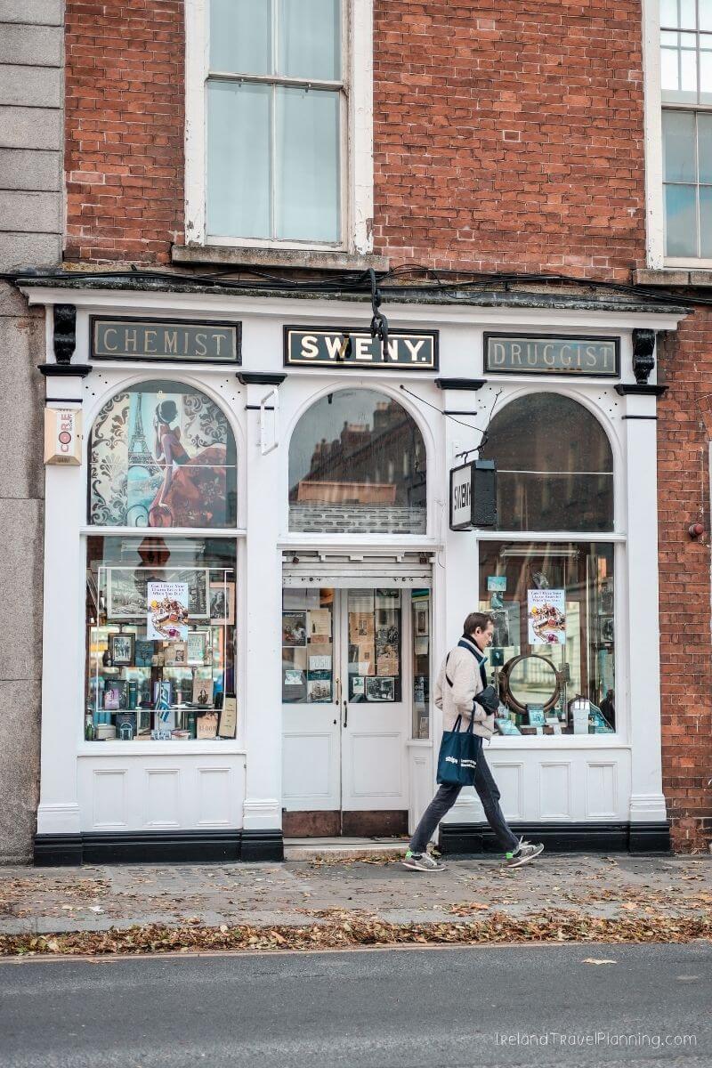 Sweeny's Chemist & Druggist shop front with a person walking by