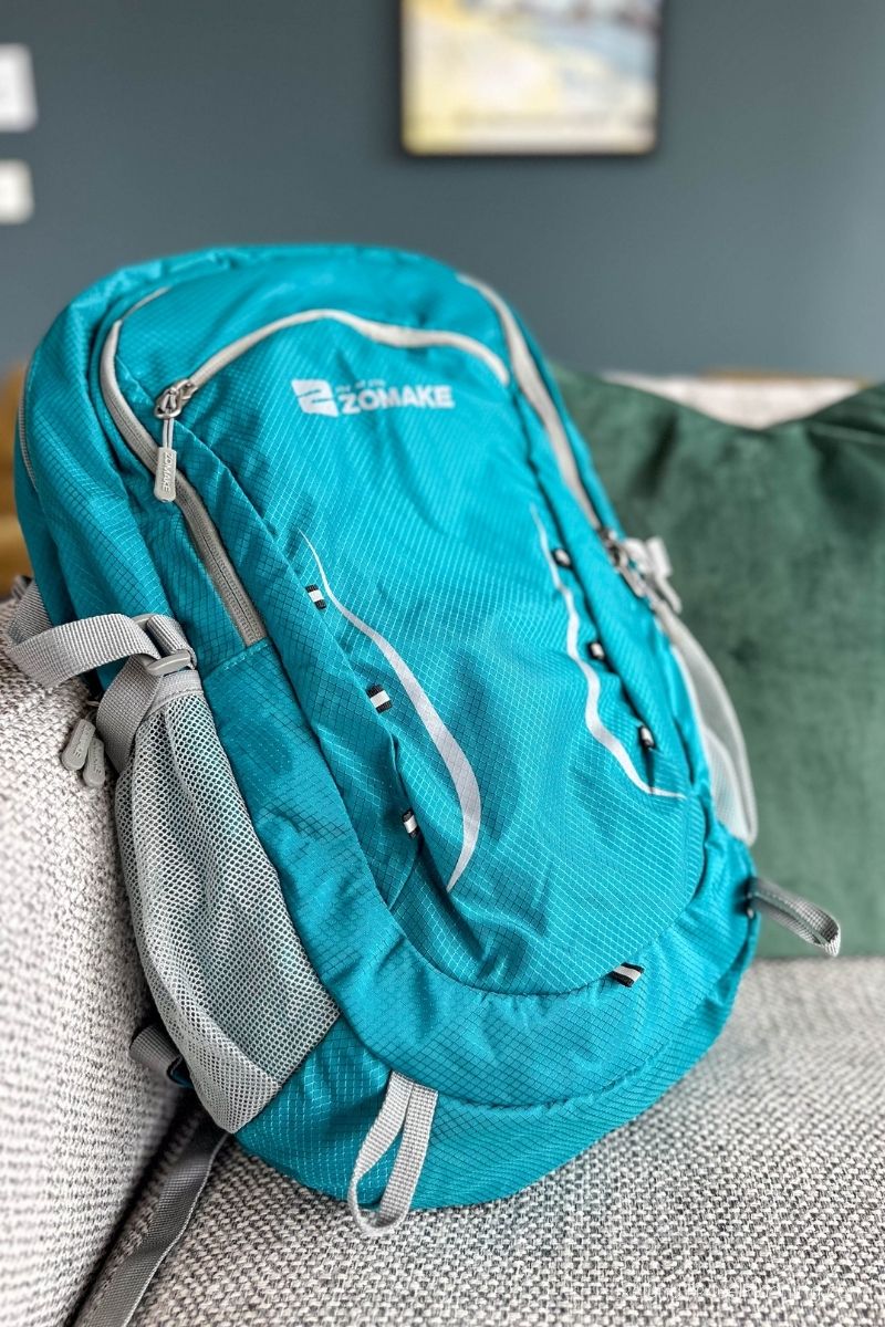Teal Zomake hiking backpack with mesh pockets on a couch