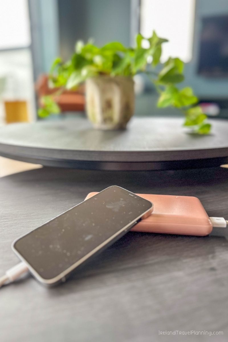 iPhone charging on a pink power bank on a dark table