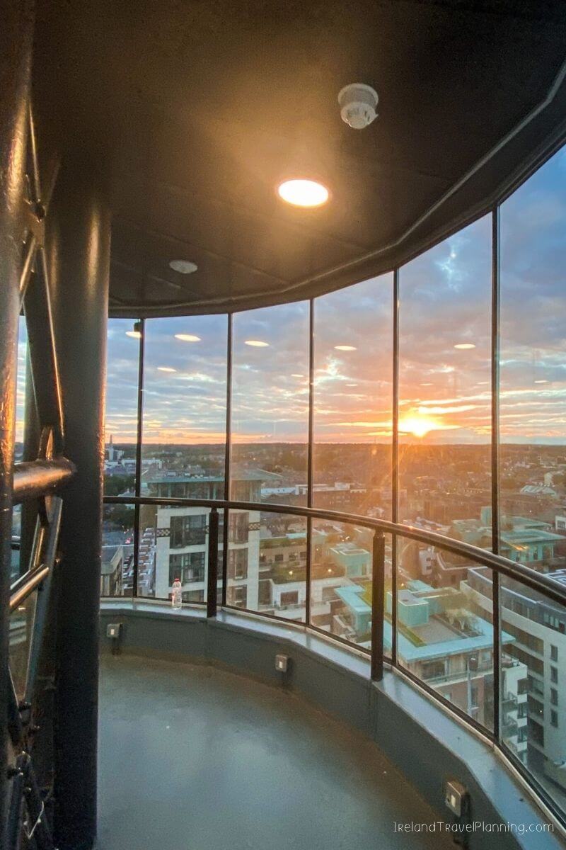 Sunset over Dublin cityscape viewed from a modern observation deck with glass railings