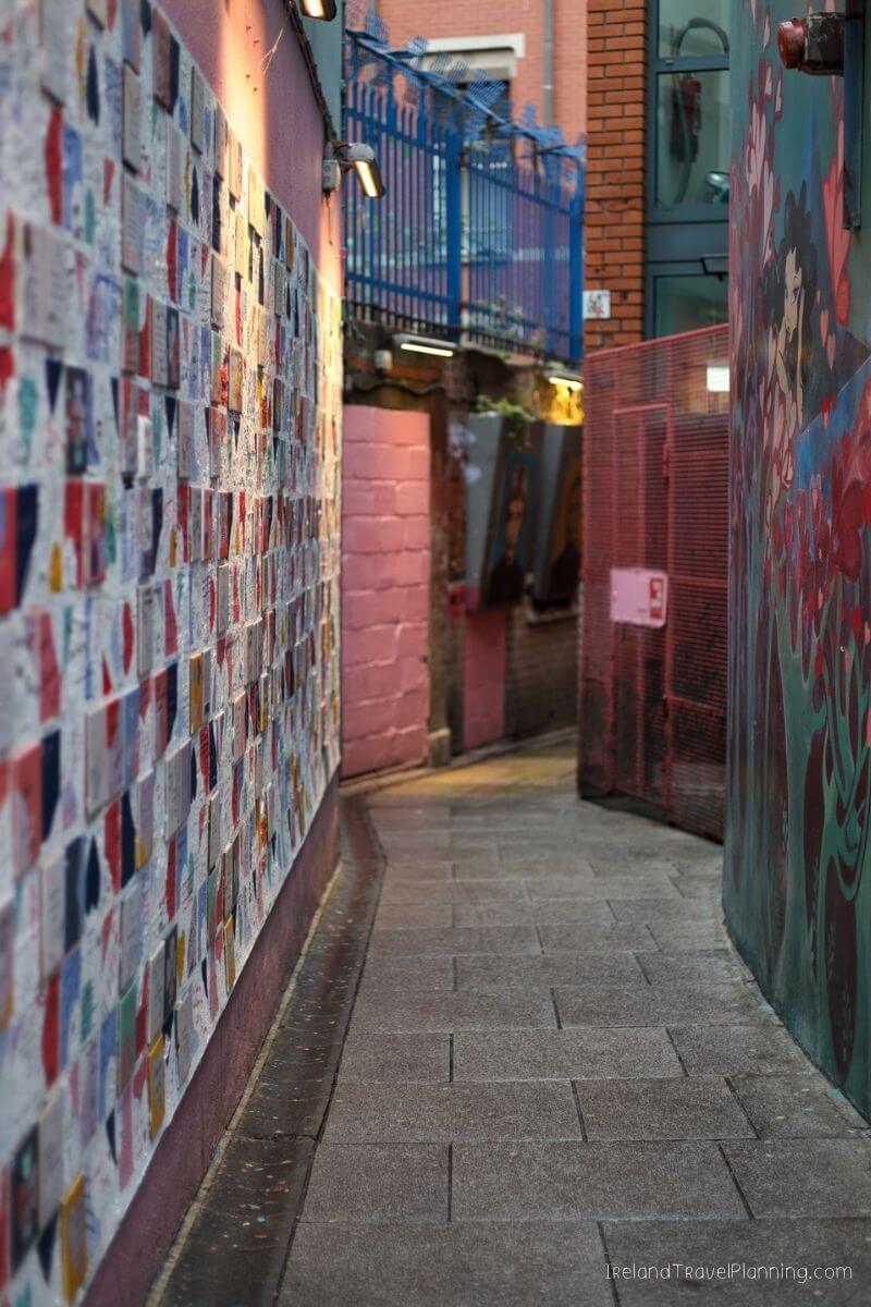 Colorful mosaic wall art on a narrow alleyway in Ireland