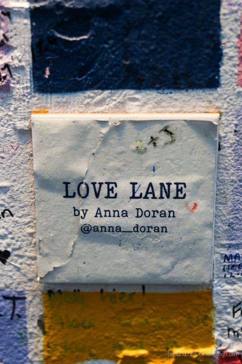 Close-up of "LOVE LANE by Anna Doran" sign on a textured wall