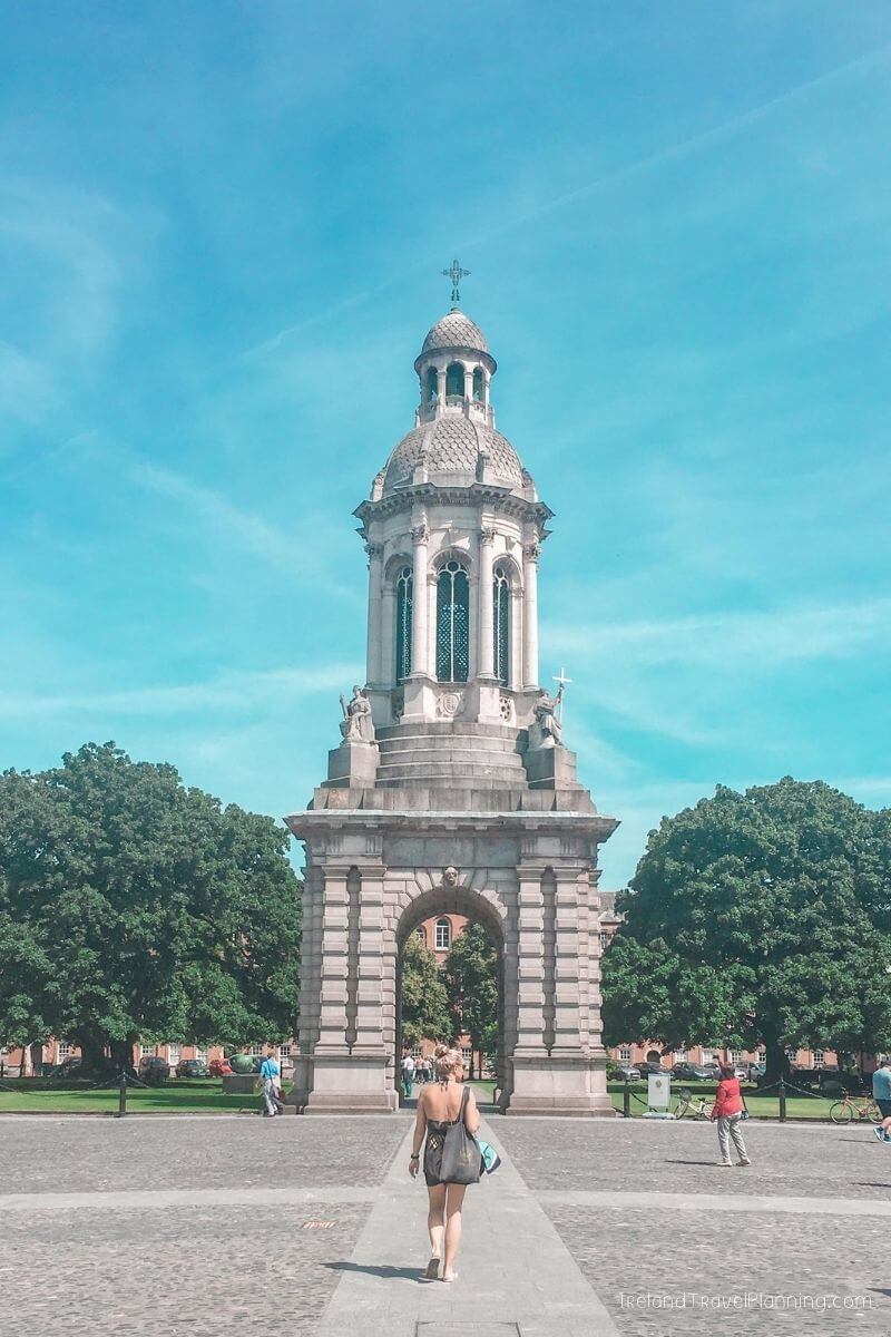 Woman walking towards the iconic Bell Tower at Trinity College Dublin