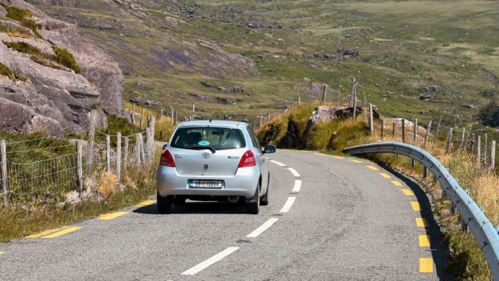 Silver car driving on winding road in rural Ireland