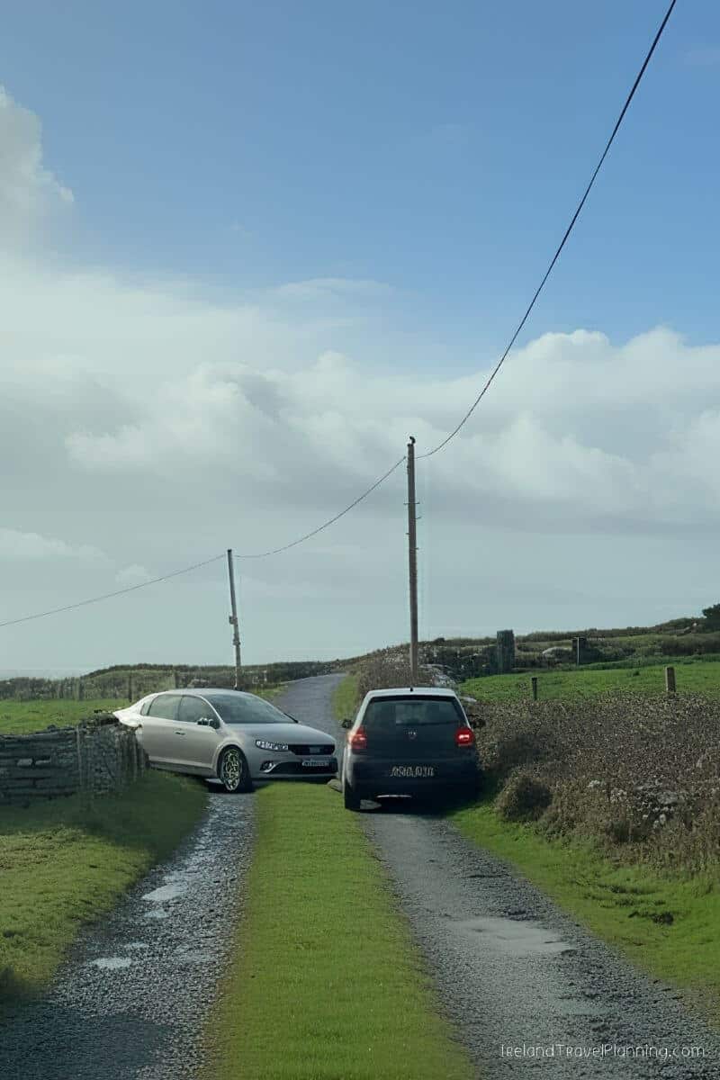 Two cars on a narrow, wet road in rural Ireland